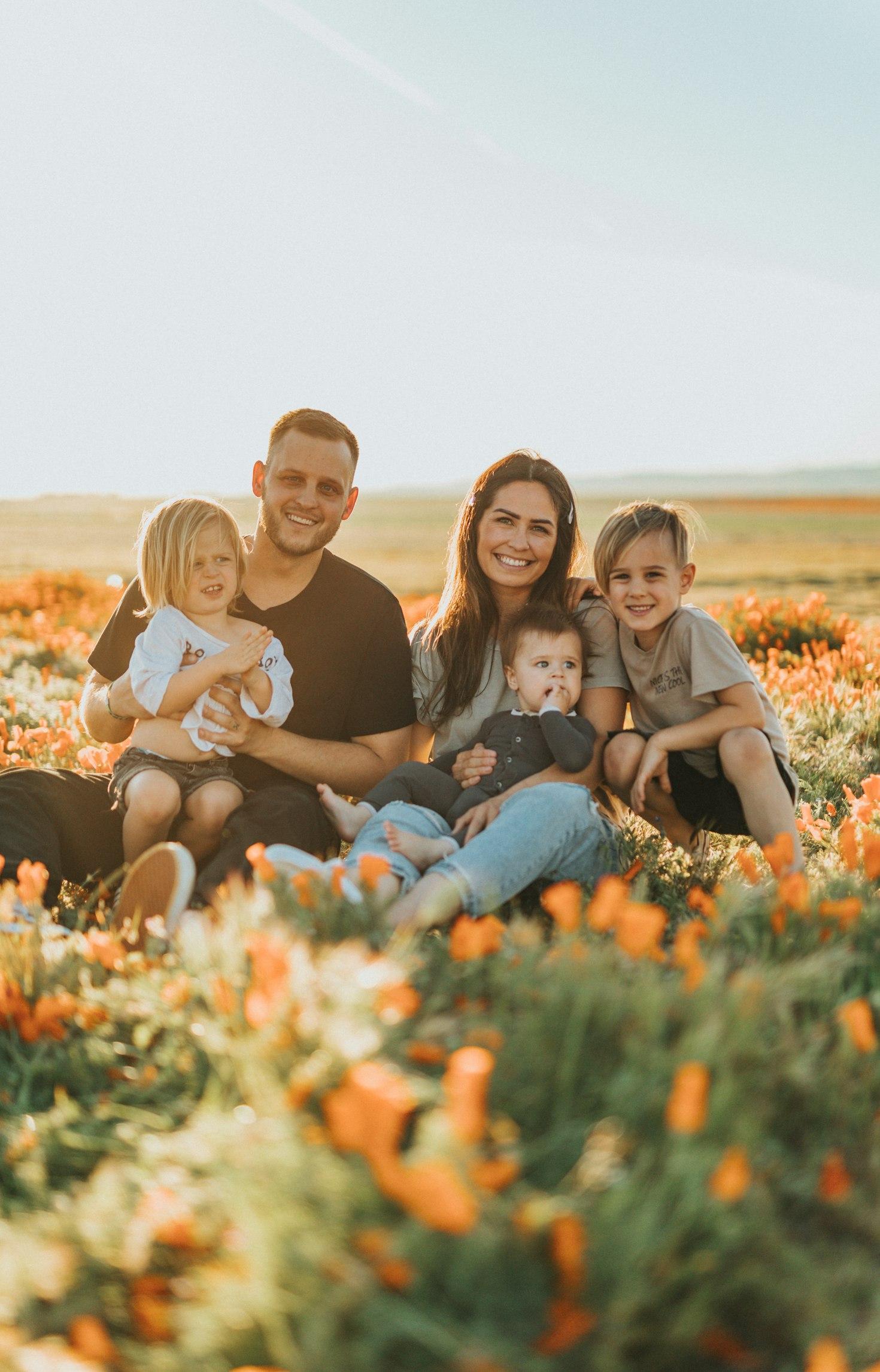 Family of five sitting together in a field of orange poppies — Sacramento family photographer