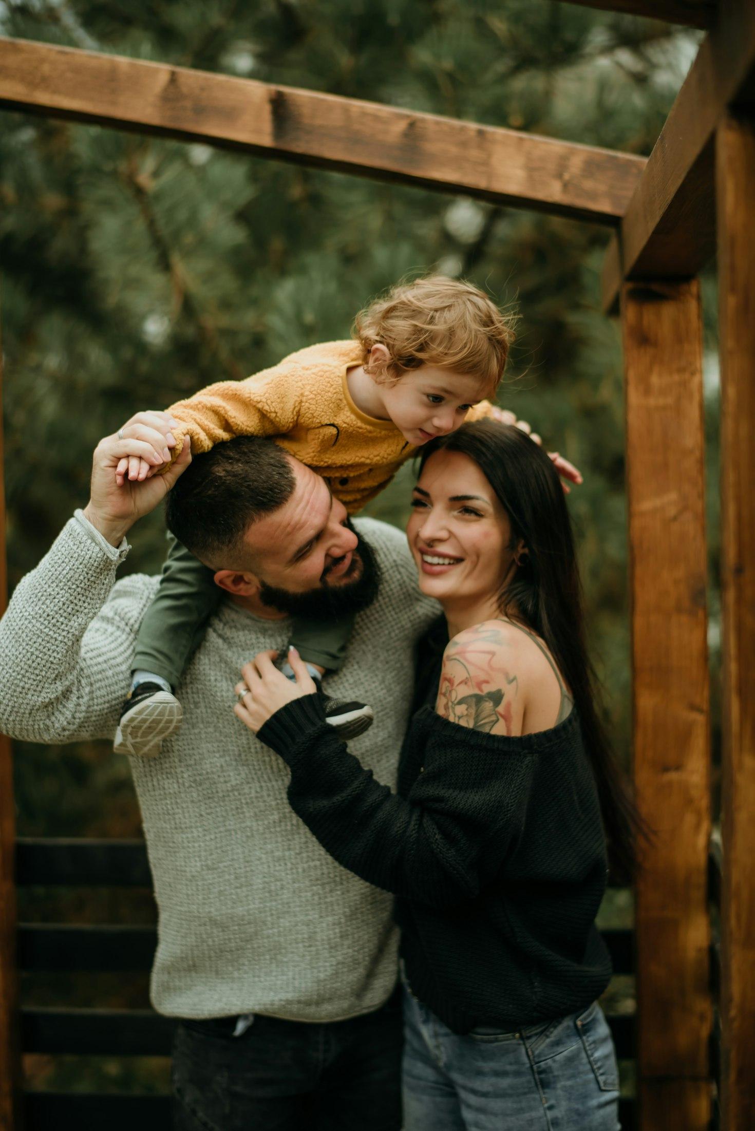 Father carrying his toddler on his shoulders while embracing mom — Sacramento family photographer
